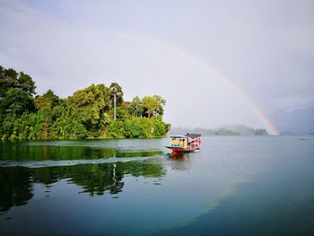 Scenic view of rainbow over river against sky