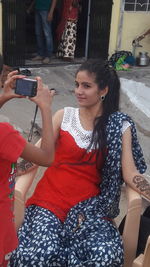 Young woman photographing while using mobile phone