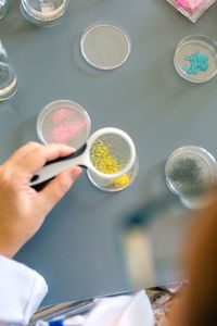 Female scientist examining golden glitter sample through a magnifying glass on pharmaceutical lab