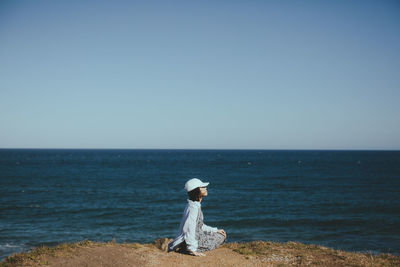 Rear view of woman looking at sea against clear sky