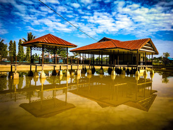 Built structure by swimming pool in lake against sky