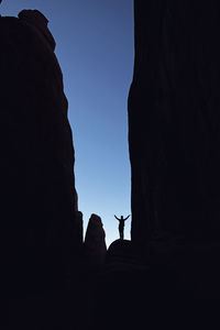 Low angle view of silhouette rock formation against clear sky