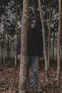 Man standing by tree in forest