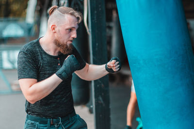 Young man practicing boxing on punching bag