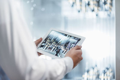 Close-up of man holding tablet at machine in factory