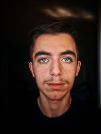 Close-up portrait of young man against black background