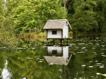 Built structure by lake against trees and plants