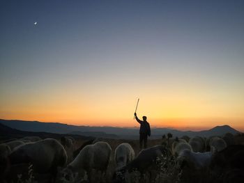 Silhouette man standing on landscape against sky during sunset