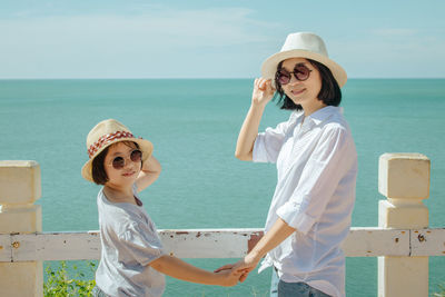 Mother and daughter wearing hats and sunglasses on sunny day