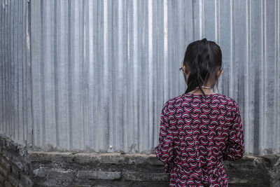 Rear view of woman standing against wall