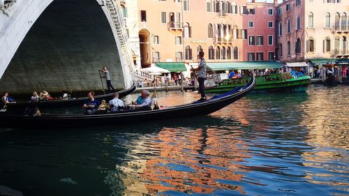 People in canal against buildings in city