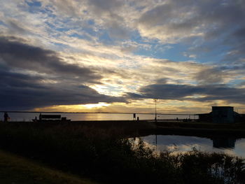 View of calm sea against cloudy sky during sunset