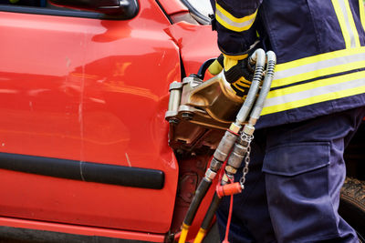 Midsection of firefighter working on car