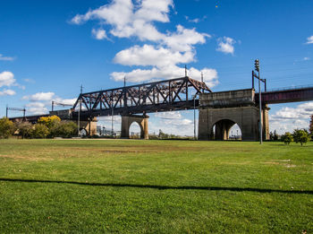 Arch bridge on field against sky