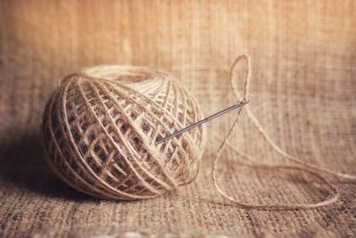 Close-up of string and sewing needle on burlap