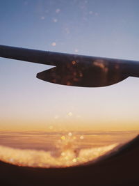 Close-up of airplane window against sky during sunset