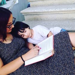 Mother reading book to son while sitting on steps