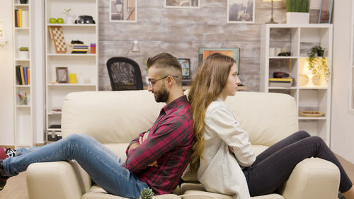 Young woman using phone while sitting on sofa at home