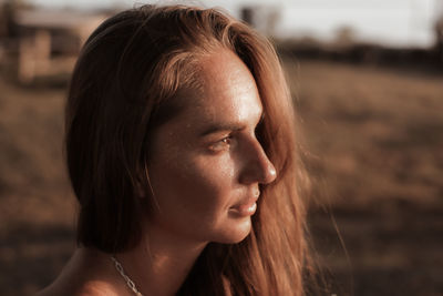 Close-up of young woman looking away standing outdoors