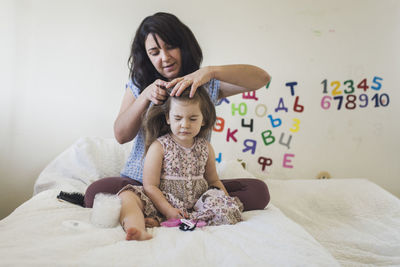 Full length of mother and daughter on bed