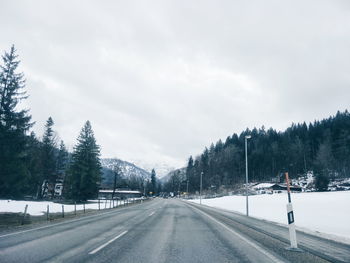 Road by snow covered mountain against sky