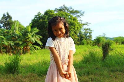 Portrait of smiling girl standing on grassy field