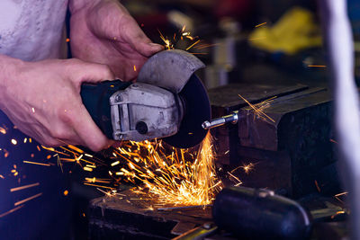 Midsection of man cutting metal in workshop