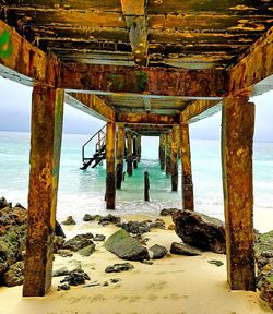 Silhouette of pier on beach against sky