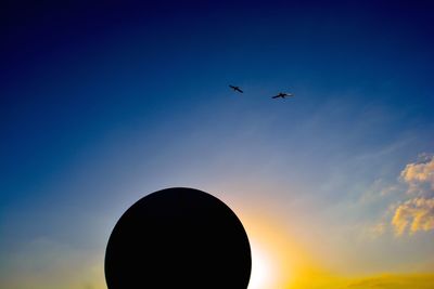 Low angle view of silhouette birds flying against sky