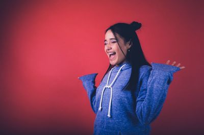 Full length of smiling young woman against red background