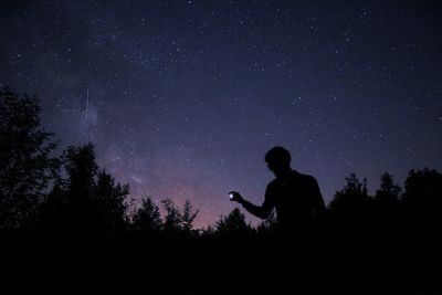 Silhouette man standing against star field at night