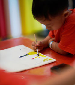 Side view of boy making drawing on table