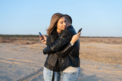 Young woman using phone while standing on land