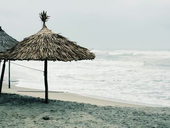 Thatched sunshades on shore against clear sky