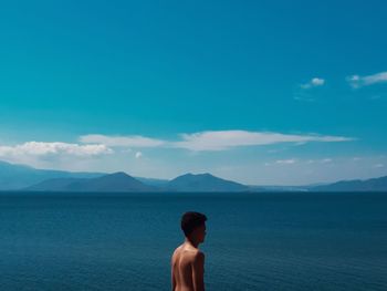 Rear view of shirtless man in sea against sky