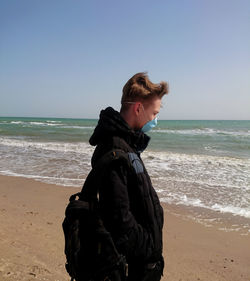 Woman standing on beach against clear sky