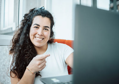 Portrait of young woman with laptop sitting at home