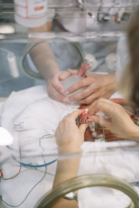 Doctor male warming up newborn's heel to collect a blood sample in incubator in clinic