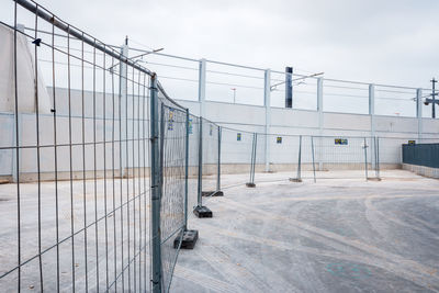 Metal fence by building against sky