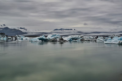 Surface level of frozen lake against cloudy sky