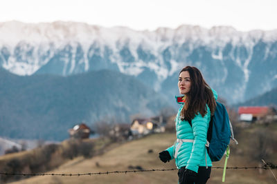 Woman hiking in winter and admiring the amazing view towards the mountains in sunset light.