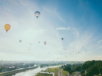 Hot air balloons flying in city against sky