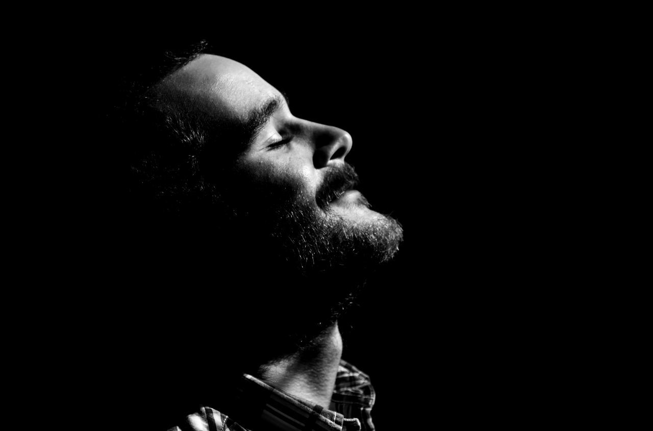 studio shot, headshot, black background, lifestyles, close-up, young adult, person, human face, serious, young men, indoors, head and shoulders, copy space, front view, leisure activity, contemplation, side view, bad habit