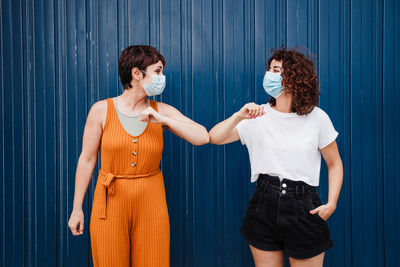 Full length of smiling young woman standing against blue wall