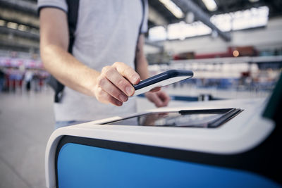 Hand of man during using self service check-in. passenger scanning ticket on smart phone at airport.