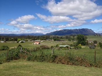 Scenic view of field and houses against sky