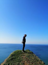 Full length of man standing on sea against clear blue sky