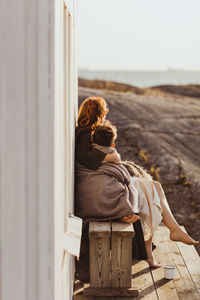 Mother sitting with son on seat by built structure