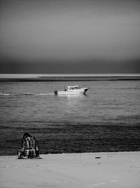 Rear view of people sitting on boat at beach