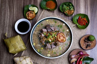 Coto makasar and ketupat, indonesian traditional food, taken with high angle view on table